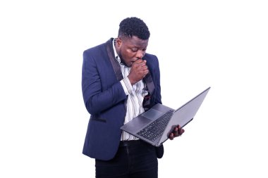 Genç, şaşkın iş adamı şık bir takım elbise giyiyor ve elleri ağızda dizüstü bilgisayara bakıyor..