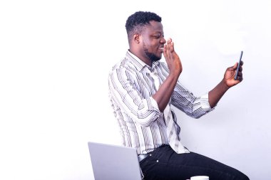 Genç, gülümseyen bir işadamı cep telefonuyla yaptığı video görüşmesi sırasında elini kaldırıyor..