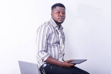 Genç, ciddi bir iş adamı elinde dijital tabletle kameraya bakıyor..