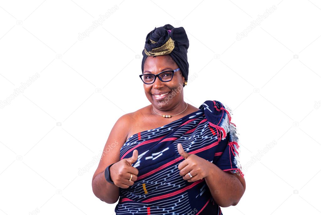 a beautiful african woman in traditional dress standing on white background raising thumbs up smiling.