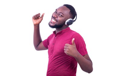 Kırmızı tişört giyen, kulaklıkla müzik dinleyen ve kameraya gülümseyen yakışıklı genç adam..