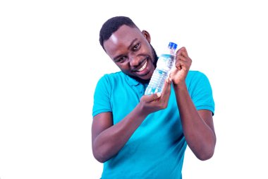 Mavi tişört giyen yakışıklı genç adam elinde bir şişe maden suyu ile gülümsüyor..