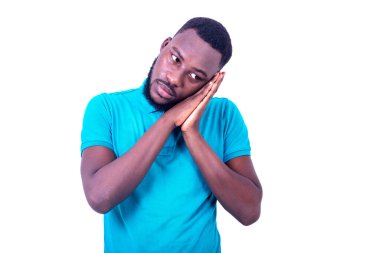 Mavi tişört giyen yakışıklı genç adam, elleri yanağının altında..