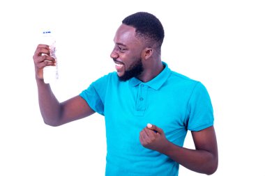 Mavi tişört giyen yakışıklı genç adamın portresi. Gülümserken bir şişe maden suyuna bakıyor..