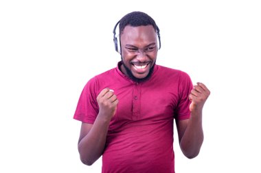 Yakışıklı, mutlu, kırmızı tişörtlü, kulaklıkla müzik dinleyen ve gülümseyen genç bir adam..