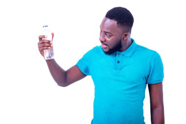 Mavi tişört giyen yakışıklı genç adam gülümserken bir şişe maden suyuna bakıyor..