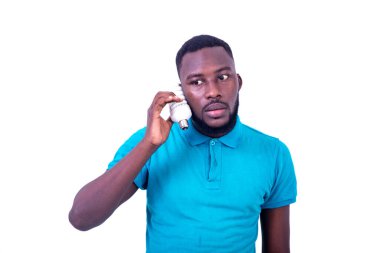 Yakışıklı, ciddi, mavi tişörtlü, kulağının yanında ampul tutan genç bir adam..