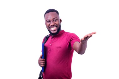 Beyaz bir arka planda duran tişörtlü genç bir öğrenci sırt çantası ve kitaplarla kameraya uzanıyor ve gülümsüyor..