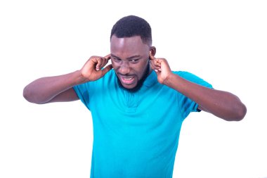 Sinirli mavi tişört giyen genç adamın portresi parmaklarla kulakları kaplayan.