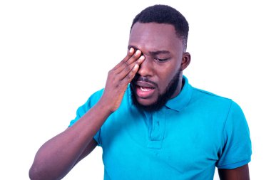 Mavi tişört giyen üzgün genç adamın portresi, eliyle gözüne dokunuyor..