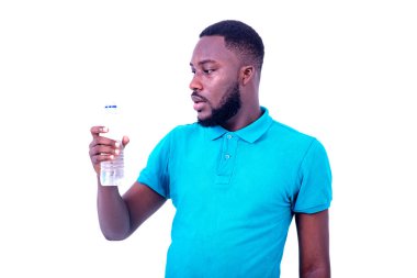 Mavi tişört giyen yakışıklı genç adamın portresi, maden suyu şişesine bakıyor..