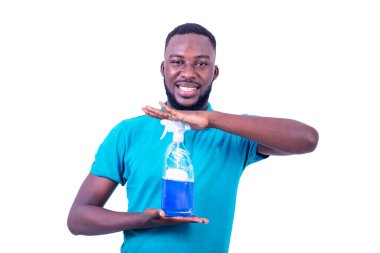 Mavi tişört giyen yakışıklı bir gencin portresi. Elinde bir şişe temizlik deterjanı tutarken kameraya gülümsüyor..