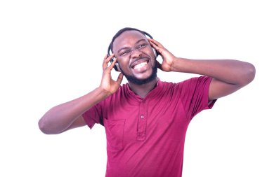 Kırmızı tişört giyen, kulaklıkla müzik dinleyen, gülümseyen yakışıklı genç adam..