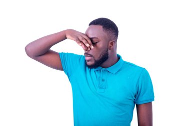 Genç adam mavi tişört giyiyor, pis ve iğrenç bir koku alıyor, parmakları burnunda nefesini tutuyor..