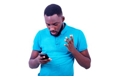 Mavi tişört giyen yakışıklı, şaşırmış genç adam, cep telefonu ekranına bakıyor..