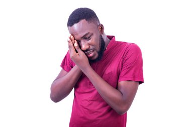 Yakışıklı, genç sakin bir adam, kırmızı tişört giyiyor, elleri gözlerinde yaralı gözleri var..