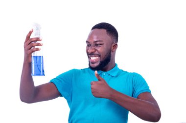 Yakışıklı, ciddi, mavi tişört giyen, elinde bir şişe temizlik deterjanı tutan ve gülümseyen genç bir adam..