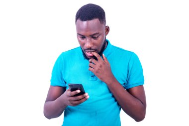 Mavi tişört giyen yakışıklı bir gencin portresi, cep telefonu ekranına bakıyor..