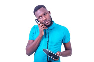 Mavi tişörtlü genç iş adamı beyaz arka planda telefonda konuşuyor.