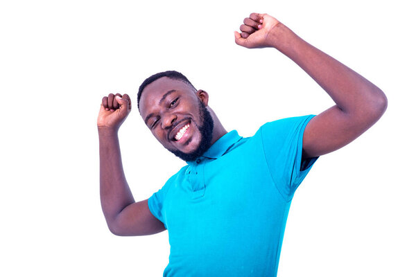Handsome happy young man wearing blue t-shirt making winning gesture with raised arms and smiling at camera.