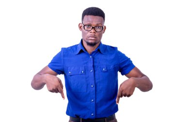 Gerçekten genç bir adam, optik gözlük takıyor, kameraya bakarken parmaklarını aşağı gösteriyor..