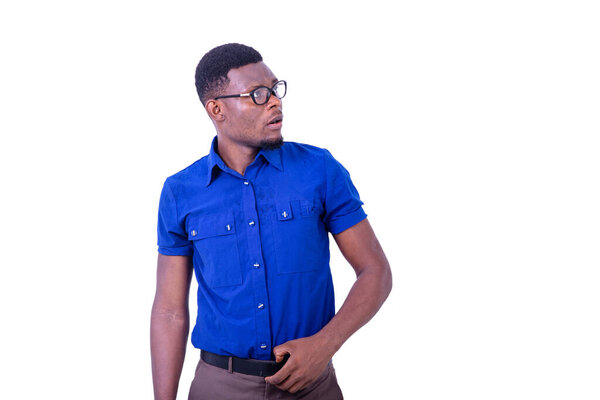 Surprised young man wearing optical glasses, looking aside while touching a belt on his jeans.