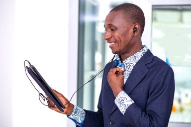 Ofiste dijital tablet kullanan genç bir işadamı müşterisinin gülümsemesiyle video görüşmesi yapıyor..