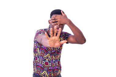 Beyaz arka planda duran gözlüklü genç bir adam reddedilme jestini gösteriyor.