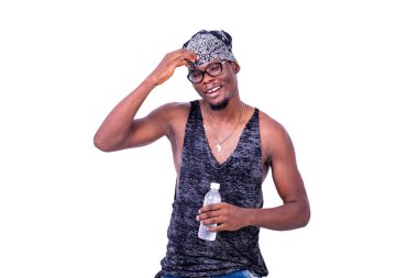 Askılı tişört giyen yakışıklı genç adam ve bandana kafasında bir şişe maden suyu tutarken gülümsüyor..