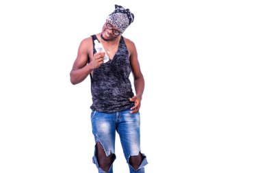 Askılı tişört giyen yakışıklı genç bir adam ve kafasına bandana takmış gülümserken bir şişe maden suyuna bakıyor..