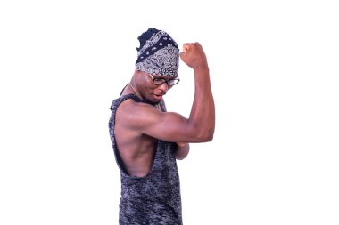 Genç, sıradan bir adam beyaz arka planda duruyor. Bandanalı, gülümseyen kaslarını gösteriyor.