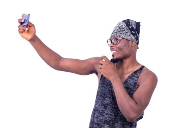 Bandanalı genç bir adam beyaz bir arka planda durup gülümsüyor.