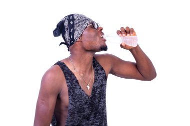 Yakışıklı, susamış, kolsuz tişörtlü ve bandanalı genç adam bir şişe maden suyu içiyor..