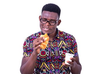 Beyaz arka planda duran gözlüklü yakışıklı genç bir işadamı elinde kruvasan ve gülümseyen bir süt kavanozu tutuyordu.