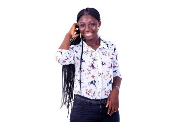 Uzun kollu bir gömlek giyen güzel bir kadın beyaz bir arka planda durup kameraya bakıp gülümsüyor..