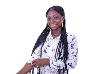 Beyaz bir arka planda duran güzel bir genç kadın gömleğinin kolunu düzeltiyor ve kameraya bakıyor, gülümsüyor..