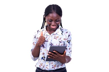 Gömlekli genç bir iş kadını izole edilmiş beyaz bir zeminde elinde tabletle durup gülümserken iyi bir jest yapıyor..