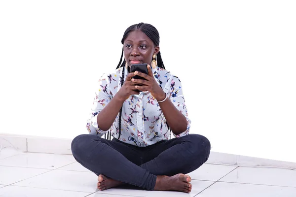 横脚で床に座りながら携帯電話でおしゃべりをしている美しい若い女性の肖像画です — ストック写真