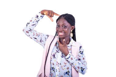 Beyaz arka planda duran ceketli genç ve güzel bir iş kadını gülümserken büyük boy işareti gösteriyor..