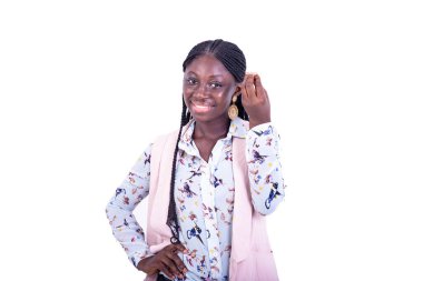 Ceketli genç ve güzel bir iş kadını beyaz arka planda duruyor parmaklarıyla işaret ediyor ve gülümsüyor..