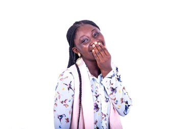 Beyaz arka planda duran genç bir kadın. Ağzını eliyle kapatıyor ve gülüyor..