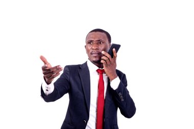 Ceketli yakışıklı bir işadamı beyaz arka planda duruyor cep telefonuyla iletişim kuruyor ve el hareketi yapıyor..