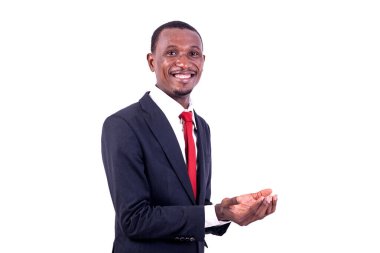 Beyaz arka planda duran ceketli bir işadamı boş elini açıyor ve gülümseyen kameraya bakıyor..