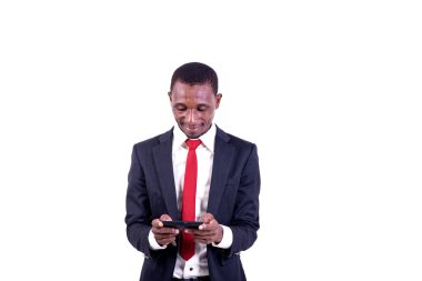 Beyaz arka planda duran bir işadamı cep telefonuna bakıp gülümsüyor..