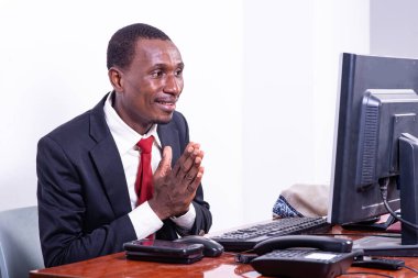 Yakışıklı, yetişkin bir işadamı ofiste dizüstü bilgisayara bakarken el ele dua ediyor..