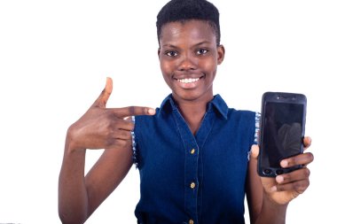 Kameraya gülümserken cep telefonu ekranını gösteren güzel bir genç kadının portresi..