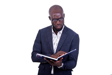 Beyaz arka planda duran ceketli genç bir işadamı klasörü kontrol ediyor..