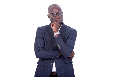 Gri takım elbiseli genç bir işadamı beyaz bir arka planda eli çenesinin altında ve hoşnutsuzlukla başka yere bakıyor..