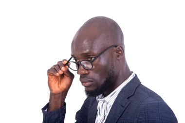 Gri takım elbiseli genç bir işadamı beyaz arka planda durup gözlüklerine dokunuyor..