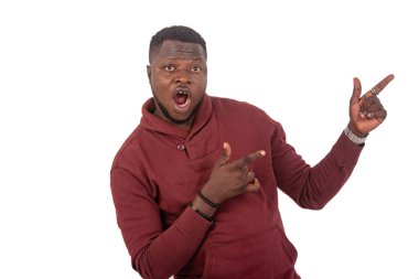 young man is screaming with fingers pointing aside while looking at the camera.